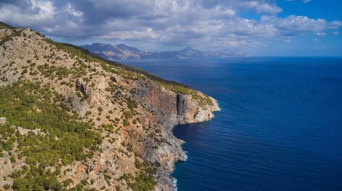 Drone shot, coastal landscape with rocky cliffs, blue sea and cloudy sky, drone shot, rocky coast,
