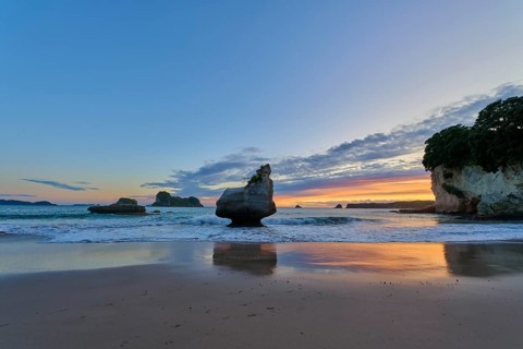 Ocean view with large rocks in the water under a dramatic sunrise sky, Cathedral Cove, Coromandel,