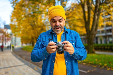Mature man tourist checking the pictures on the screen of a camera while photographing the city