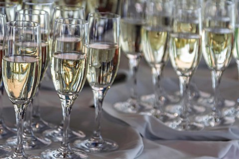 Several full champagne glasses stand on a table and reflect the light, champagne reception,