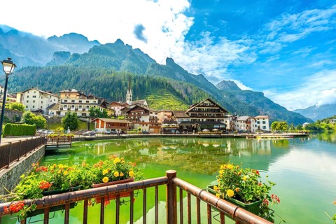 Picturesque village of alleghe reflecting on the lake with the dolomites in the background during a