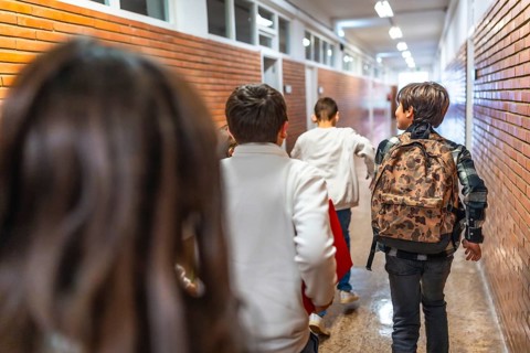 Pupils running down school hallway after class bell rings, eager to get home or to extracurricular