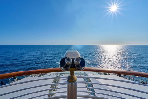 View from the ship's deck, Mein Schiff 6, under bright sunshine and blue sky, binoculars at the