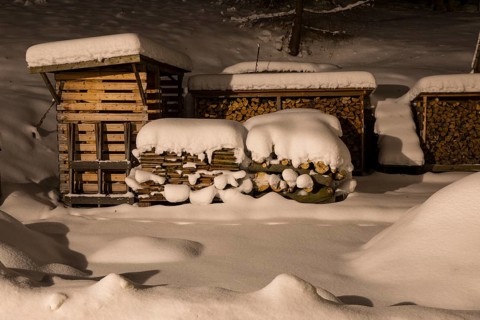 Several snow-covered piles of wood at night, wood in front of the hut, Oberlochmühle,