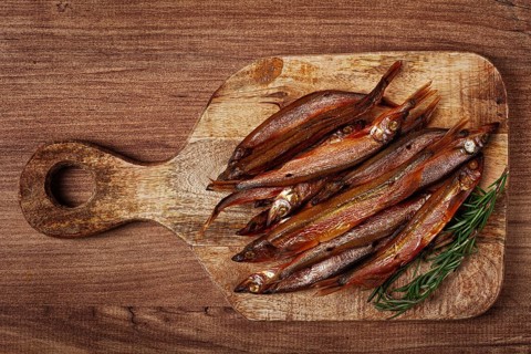 Cold smoked capelin, on a wooden chopping board, no people