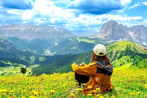 Hiker enjoying the stunning view of the seceda mountains in the dolomites during summer, surrounded