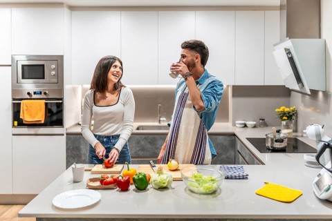 Happy couple preparing a healthy meal of fresh vegetables in their kitchen, enjoying time together