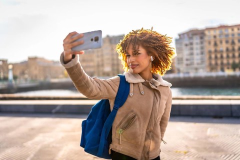 Beauty latin young woman taking selfie with smartphone enjoying sunset in the city