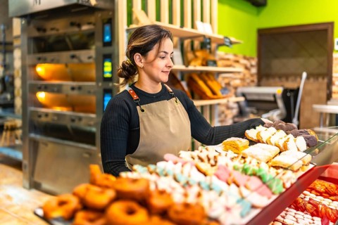 Side view photo with copy space of a latin young friendly woman selling bread and pastries in an