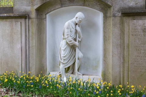 Grave with large figure of a man and spring blossom, Dresden Forest Cemetery, Saxony, Germany,