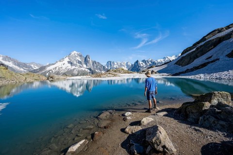 Mountaineer in front of mountain landscape with mountain lake, tourist at Lac Blanc with water