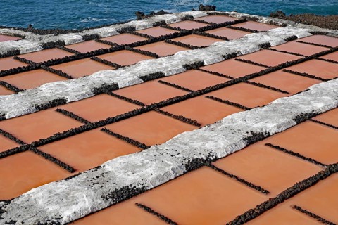 Salt pans with reddish water basins in a geometric arrangement near the sea, salt pans,