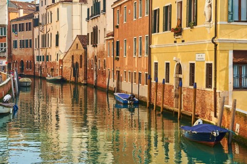 View from 'Casa di otello' over a waterway with boats lying in the water in Venice on a sunny day