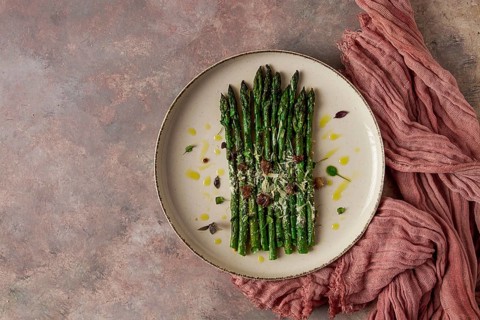 Grilled asparagus, spices and herbs, parmesan cheese, on a beige plate, top view, rustic, no people