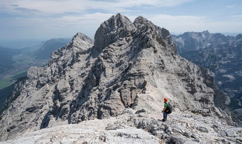 Mountaineer with helmet on a narrow rocky ridge, crossing the Jubiläumsgrat, view of rocky mountain