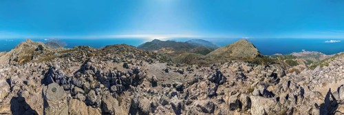 360° summit view from Kali Limni of mountains and the ocean under a blue sky, hike to the summit of