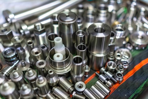 Close- up of a raw of small finished metal pieces placed on surface in metallurgic factory