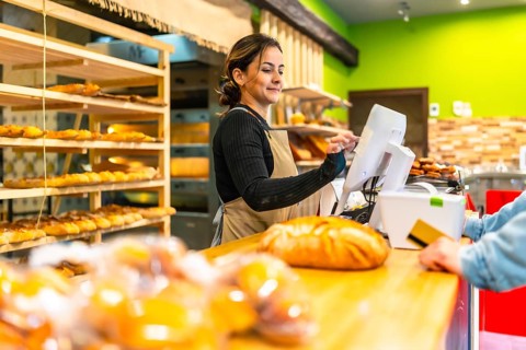 Side view photo with copy space of a latin young woman worker preparing bill for a client in an