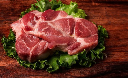 Raw pork steak, two pieces, on a wooden background