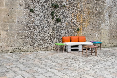 Pallet bench with colourful cushions in front of a high wall, Matera, Basalikata, Italy, Europe