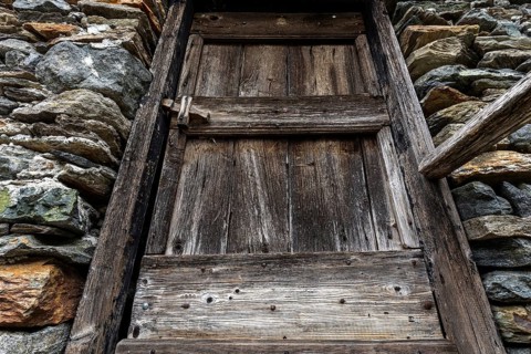 Old wooden door of a typical Ticino stone house in the mountain village of Bordei, Centovalli,