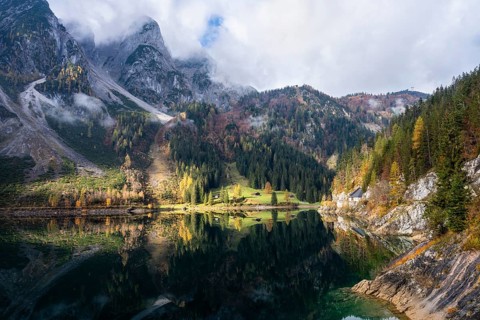 The Vordere Gosausee in autumn. The Gosaukamm on the left. Clouds and sun. Reflection. Vorderer