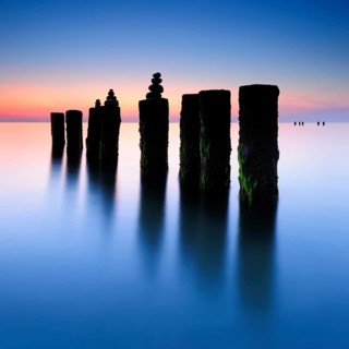 Stone pyramids on old groynes with algae in the water on the beach of the Baltic Sea, long exposure