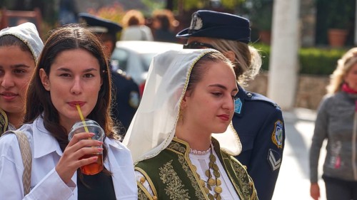 Young woman, one in traditional traditional costume, the other with a drink in her hand, on the