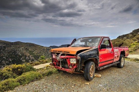 Degraded pickup truck in hilly landscape under cloudy sky, wrecked vehicle, Crete, Greek Islands,