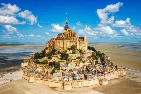 Impressive building complex on an island in a vast sandy landscape under a blue sky, Le