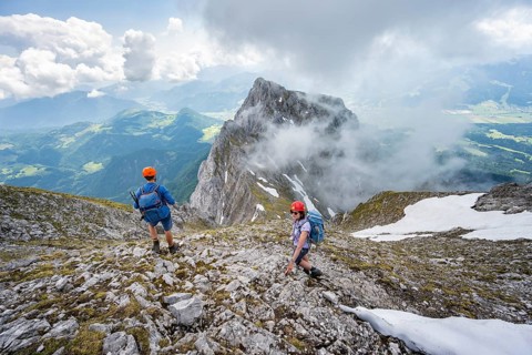 Mountaineer with helmet on a narrow hiking trail, ascent to the Ackerlspitze, clouds moving around