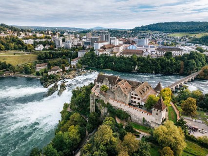Aerial view of the Rhine Falls with Laufen Castle with autumnal vegetation, on the horizon the town