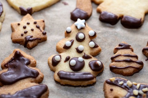 Christmas biscuits with chocolate decoration in the shape of stars and fir trees on baking paper,