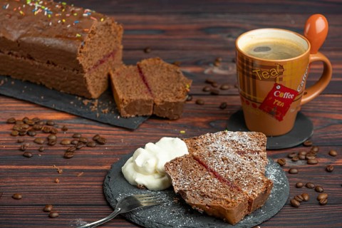 Pieces of chocolate cake with icing sugar, whipped cream and coffee beans lying around