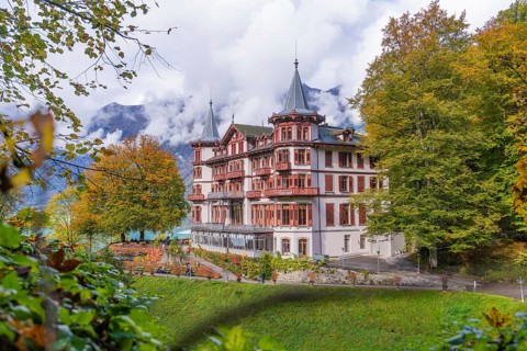 Large hotel against a mountain backdrop in autumnal surroundings with dramatic clouds, Grandhotel