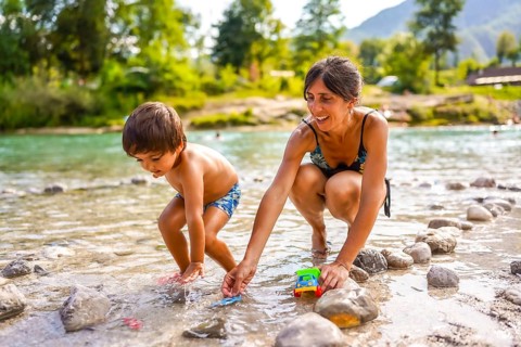 Mother and son enjoying summer holidays, playing with toy cars in the refreshing water of lake