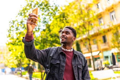 African male young traveler taking photos of a city while walking along the street