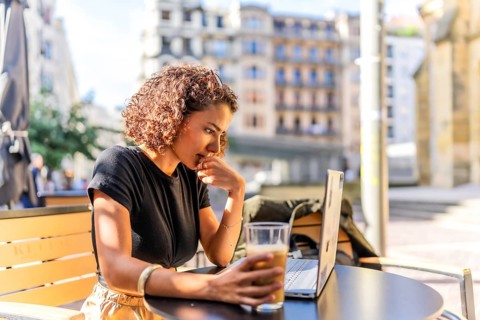 Arab young businesswoman drinking coffee sitting on a terrace working with laptop in the city