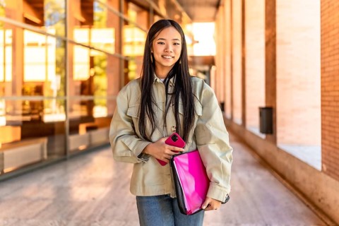 Frontal portrait of a chinese beauty female student standing smiling at camera at the university