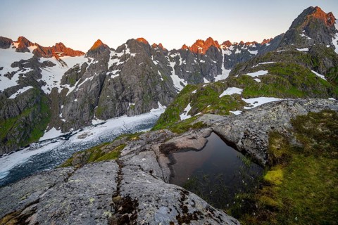 Rocky mountain peaks and Trollfjordvatnet with snow, small pond in moorland at Trollfjord Hytta,