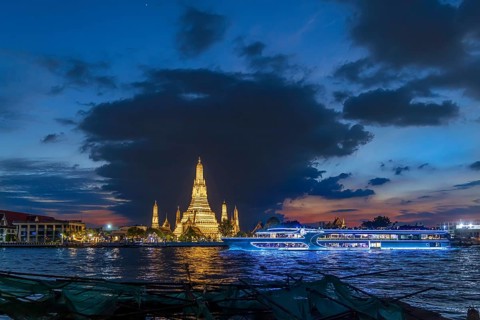 Wat Arun, Temple of Dawn at sunset with dark clouds. Boats on the Chao Phraya river. Tourist