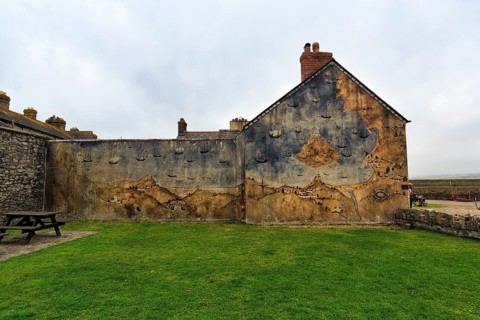 Façade with mural, St Michael's Mount, tidal island with castle, rain clouds, Marazion, Cornwall,