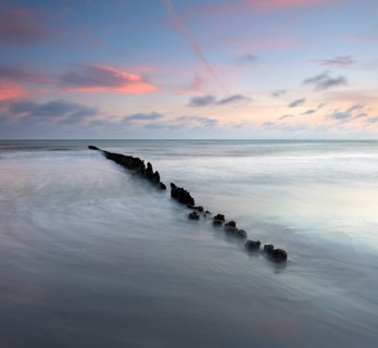 Sunset on the beach, old groyne in the surf, Klintholm Havn, Møn Island, Denmark, Europe