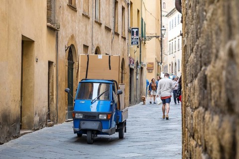 Three-wheeled Piaggio Ape van packed full in an alleyway in the historic centre of Volterra,