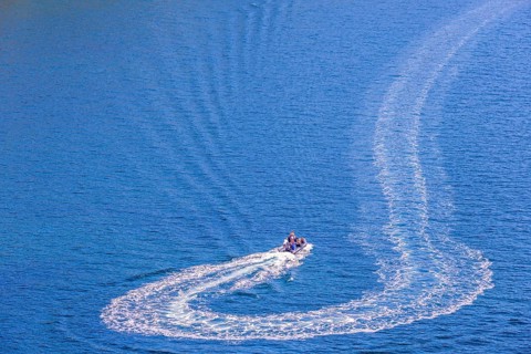 Inflatable boat with people turning on the sea and making wake pattern on the water surface, Crozon