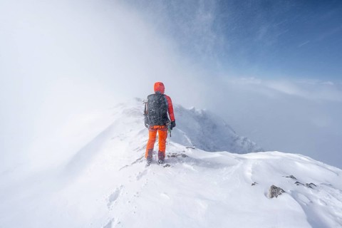 Ski tourer in snowy mountain landscape, at the summit of the Wildhorn, cloudy mood, high tour,