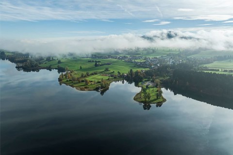 Sports facility and bathing area, lake Rottachsee, village Petersthal, mountains covered with fog,