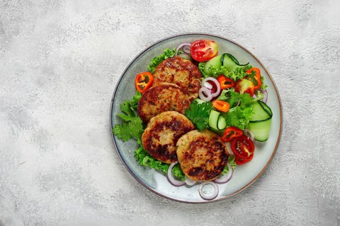 Fried chicken cutlets, minced chicken, with vegetables, on gray, with vegetable salad, top view,