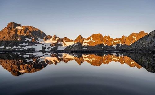 Rocky mountain peaks reflected in a small pond, mountain landscape with alpenglow at sunrise, at