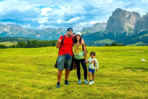 Family enjoying summer vacation hiking in alpe di siusi, with the sciliar mountain in the